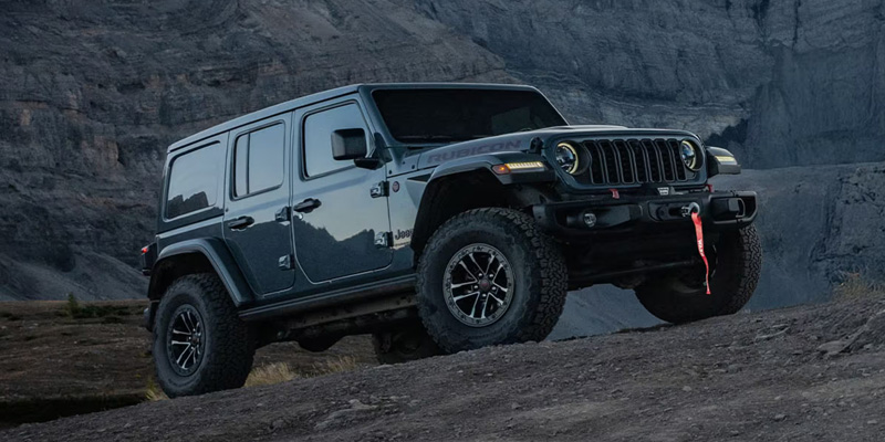 Gray Jeep Wrangler Rubicon SUV climbing rocky terrain showcasing its off-road capability and rugged design.