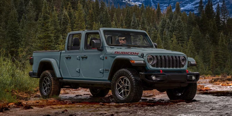 Gray Jeep Gladiator Rubicon parked on a rugged forest trail.