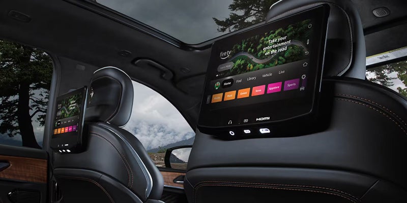 Jeep Grand Cherokee interior with rear passenger touchscreen display and panoramic roof.