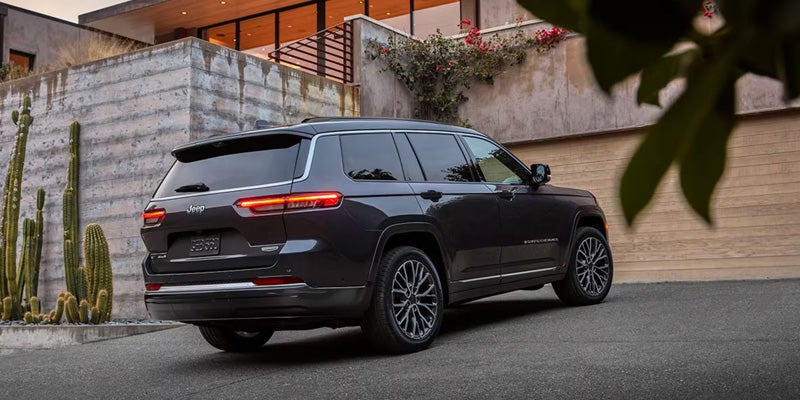 Black Jeep Grand Cherokee parked outside a modern home with sleek exterior styling.