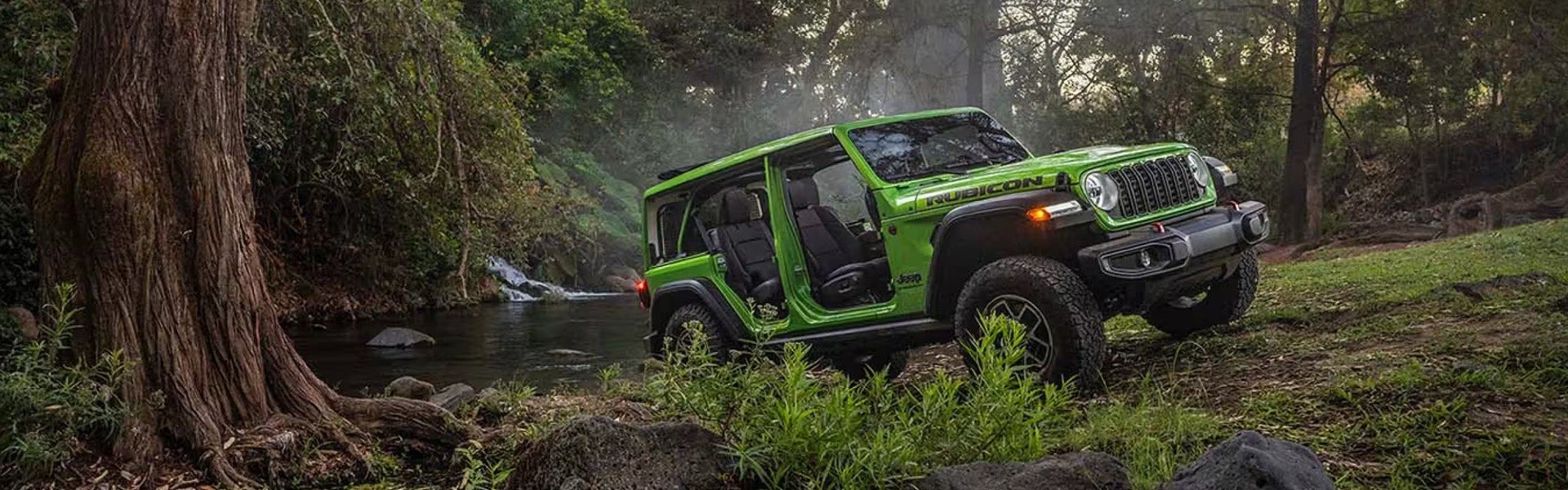 2026 Jeep Wrangler Rubicon green SUV driving through muddy trail
