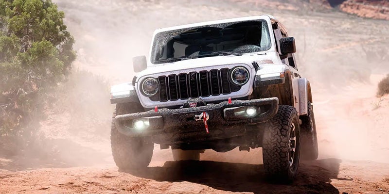 2026 Jeep Wrangler Rubicon driving through dusty off-road terrain
