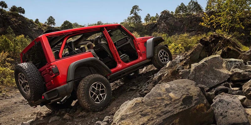2026 Jeep Wrangler Rubicon red SUV climbing rocky off-road trail
