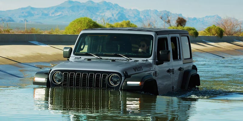 2026 Jeep Wrangler SUV driving through water off-road terrain