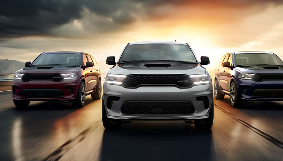 Three Dodge Durango SUVs driving side by side at sunset.
