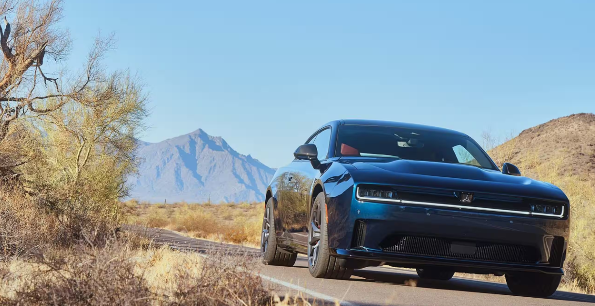 Blue Dodge Charger driving on a desert road with mountains in background.