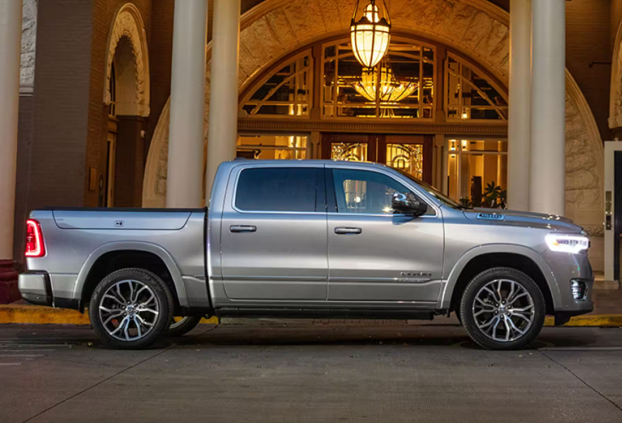 Silver RAM 1500 parked in front of an elegant building with large columns and warm lighting.