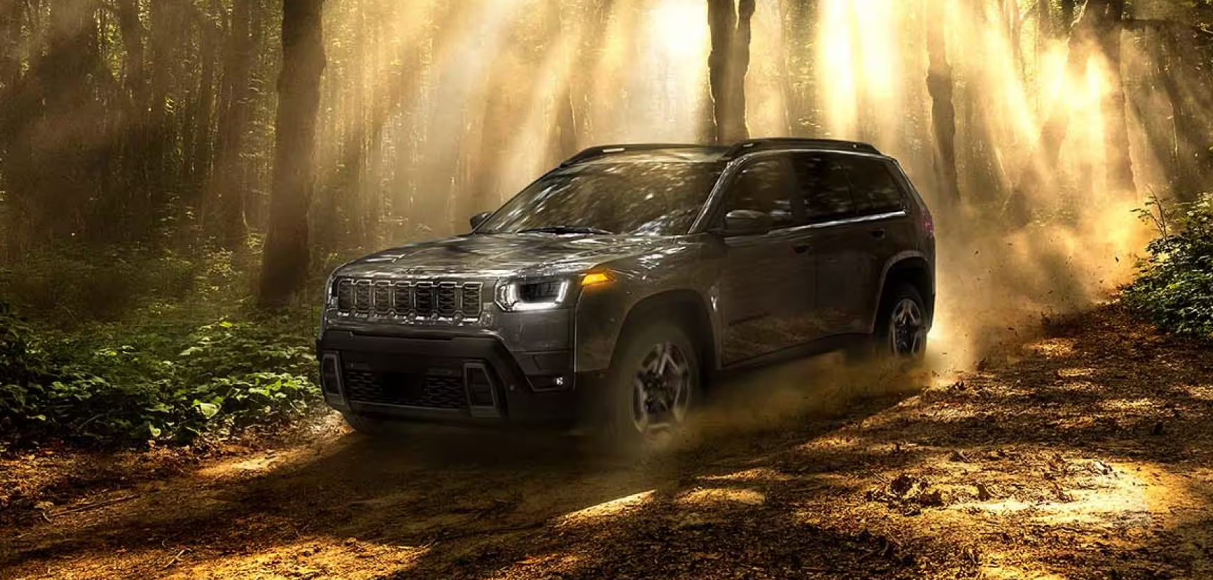 2026 Jeep Cherokee driving off-road through a sunlit forest trail.