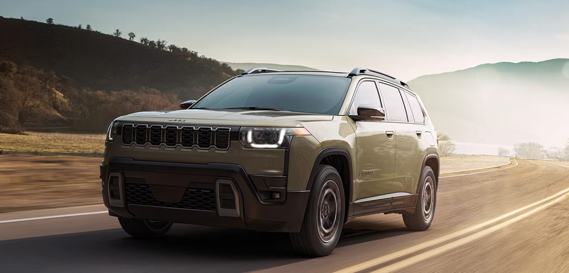 2026 Jeep Cherokee driving on a scenic rural road.