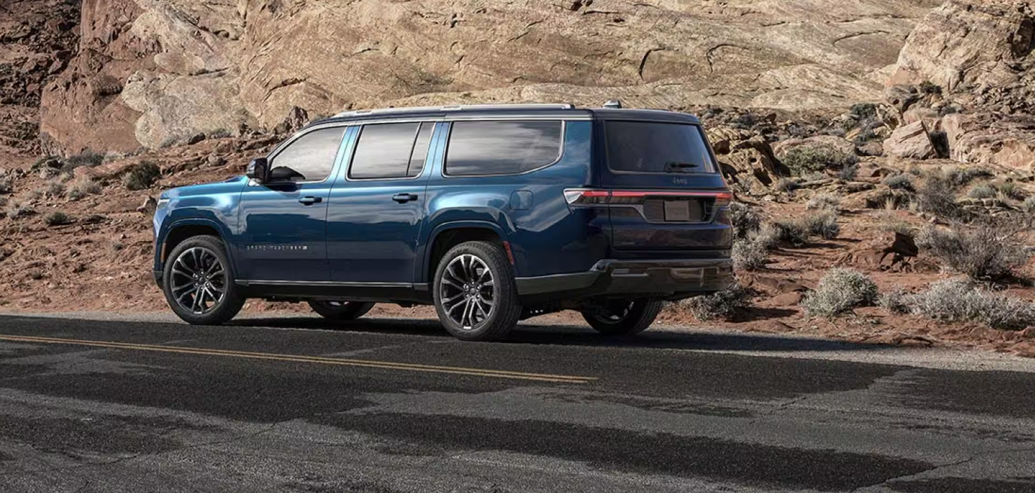Blue 2026 Jeep® Grand Wagoneer L driving on rocky highway.