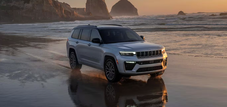 2026 Jeep Grand Cherokee SUV driving on the beach at sunset